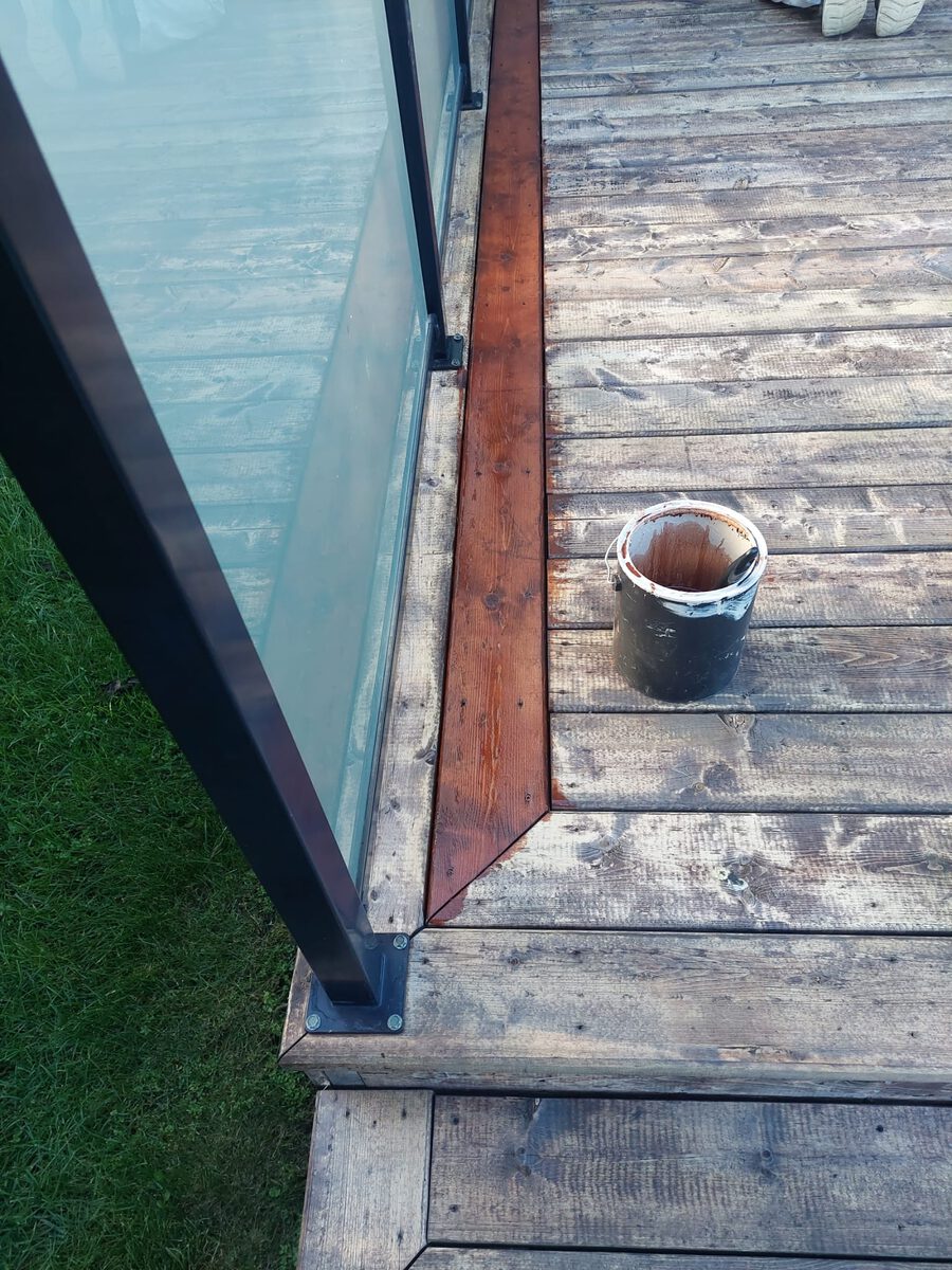 Deck staining in progress - fresh stain on weathered cedar